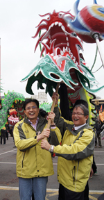 行政院客委會主委黃玉振（左）與苗栗市長（右）一同將火旁龍舉起，象徵苗栗火旁龍活動正式展開