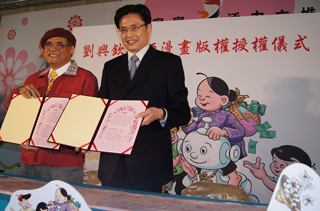 行政院客委會主委黃玉振與劉興欽老師一同出示漫畫版權授權書。