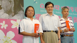 行政院客委會主委黃玉振(中)頒獎給首獎得主張家偉(左)及第二名得主李志鋒(右)。