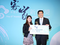 「第5屆客家新聞獎」學生組影音媒體類第一名得主彭素芬（圖左）喜極而泣，欣喜的由行政院客委會主委黃玉振手中接下獎牌及獎金