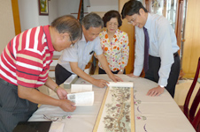 行政院客委會主委黃玉振(右)、南天書局老闆魏德文(中)及國寶級漫畫家劉興欽老師(左)一起欣賞《台灣客家喬遷圖卷》，回憶兒時客庄事。